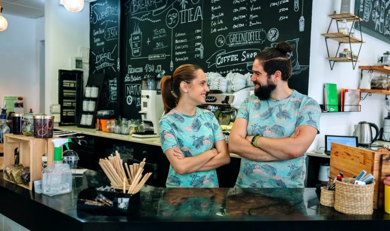 Couple of coffee shop owners posing smiling